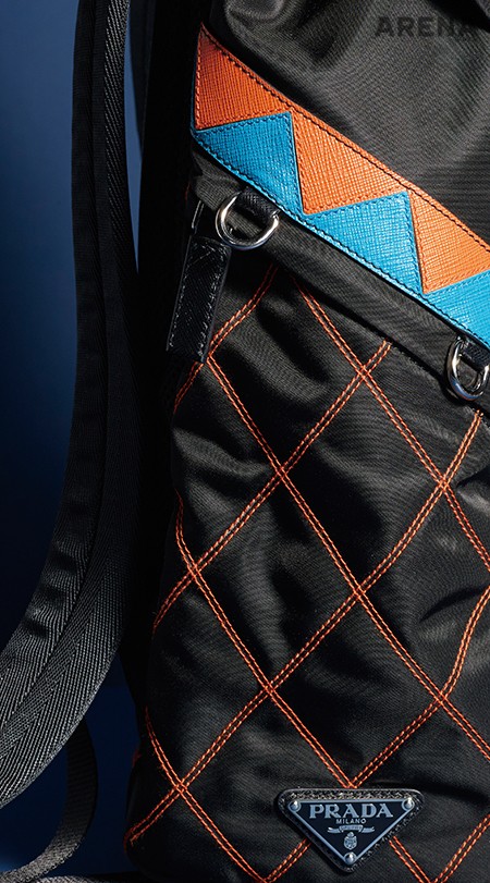 작은 고리를 여러 곳에 장식한 나일론 소재 백팩. 보색 대비가 도드라지는 지그재그 패턴의 가죽 장식이 특징이다. 가격미정 프라다 제품. 