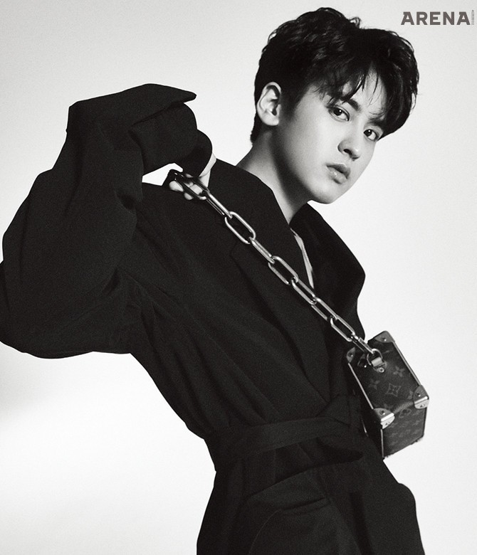 오버사이즈 재킷•검은색 셔츠•검은색 쇼츠•벨트 모두 보테가 베네타, 볼드한 체인 스트랩의 직육면체 크로스백 루이 비통 제품.